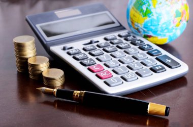 Dolma kalem ve hesap makinesi para yığını ve iş konsepti için toprak