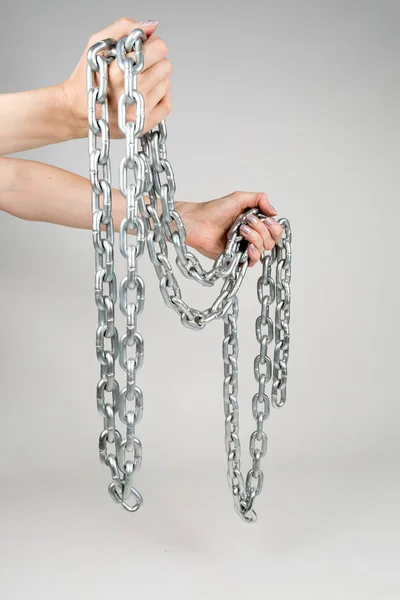 Gruesa cadena de metal en las manos de las mujeres sobre fondo blanco aislado —  Fotos de Stock