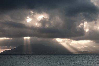 o karadeniz ve gün batımında bulutlar aracılığıyla güneş ışığında şehrin silueti