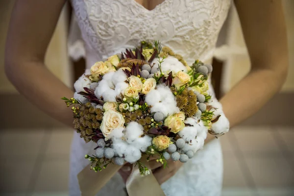 Beauty wedding bouquet with cotton and yellow roses in  the hands of bride