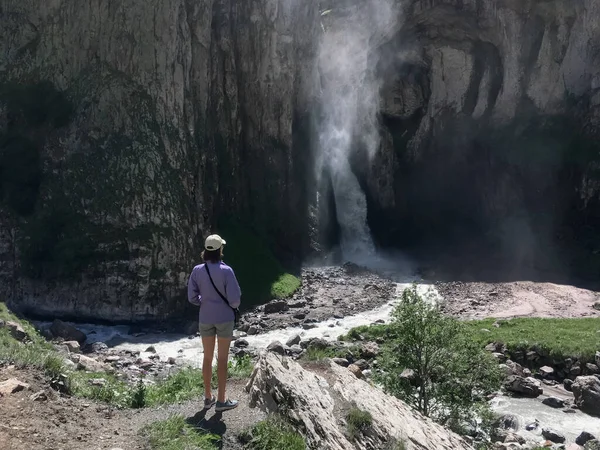 Elbrus yakınlarındaki Kafkasya dağlarında güzel bir şelaleyi izleyen bir turist kız.
