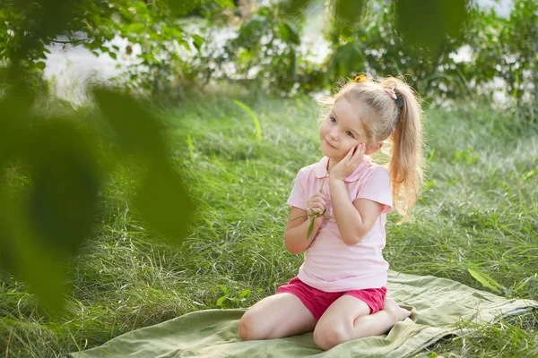 花と草の上に座って少しの幸せな女の子 夏季には庭園で 夢のような — ストック写真