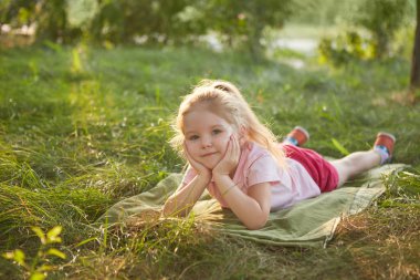 Küçük mutlu kız çim üzerinde yalan. Rüya gibi yaz bahçede.