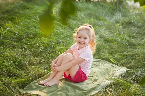 草の上に座って少しの幸せな女の子 夏季には庭園で 夢のような — ストック写真