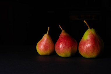 siyah arka plan üzerine üç olgun sarı armut. yakın çekim