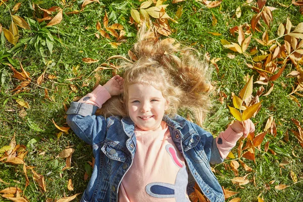 Ευτυχισμένη Κοριτσάκι Ξαπλωμένος Στο Γρασίδι Στο Φθινόπωρο Ηλιόλουστη Μέρα — Φωτογραφία Αρχείου