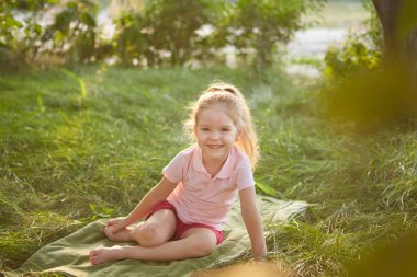 küçük kız çimlerde oturuyor