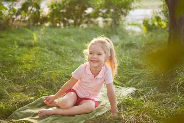 Klein meisje is zittend op het gras — Stockfoto