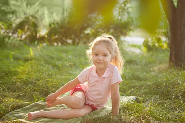 小さな女の子は草の上に座っています。 — ストック写真