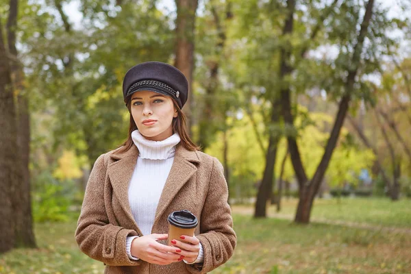 Krásná žena v podzimním parku s kávou — Stock fotografie