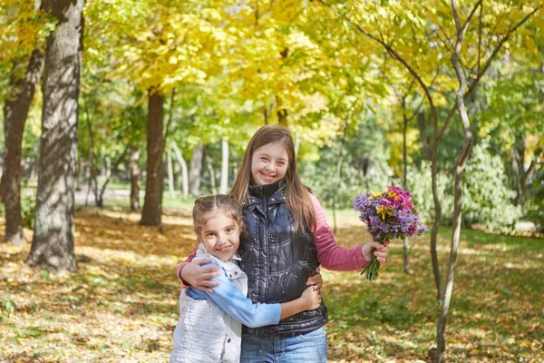 ダウン症候群の女の子と秋の公園の小さな女の子. — ストック写真