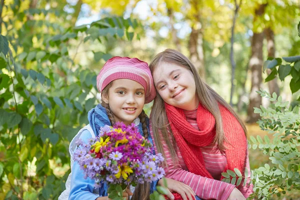 Chica con síndrome de Down y niña en el parque de otoño . — Foto de Stock