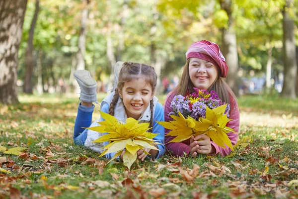 Flicka med Down syndrom och liten flicka i höst parken. — Stockfoto