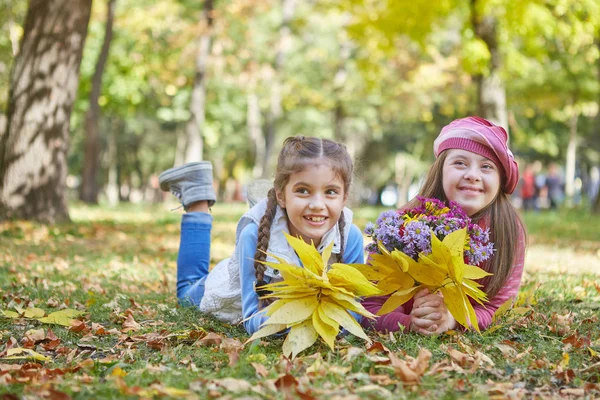 Flicka med Down syndrom och liten flicka i höst parken. — Stockfoto