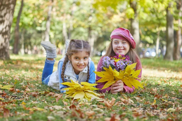 Chica con síndrome de Down y niña en el parque de otoño . — Foto de Stock