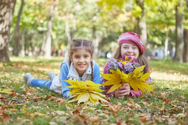 Chica con síndrome de Down y niña en el parque de otoño . — Foto de Stock