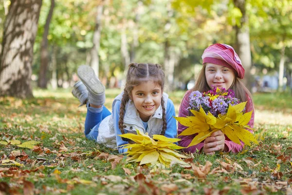 Menina com síndrome de Down e menina no parque de outono . — Fotografia de Stock