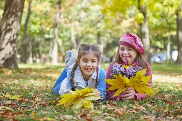 Chica con síndrome de Down y niña en el parque de otoño . — Foto de Stock