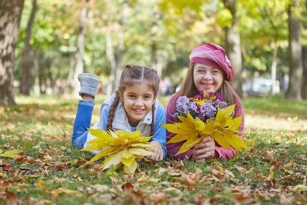 Mädchen mit Down-Syndrom und kleines Mädchen im Herbstpark. — Stockfoto