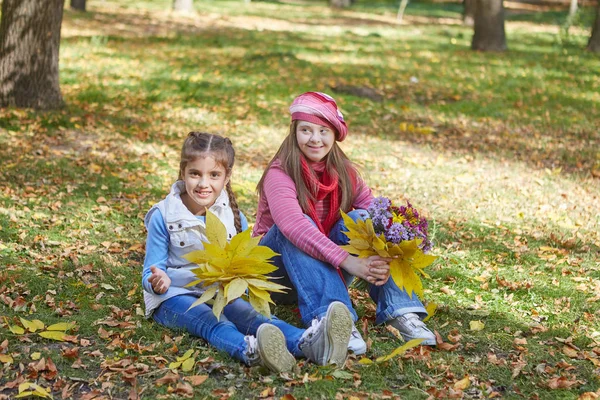 ダウン症候群の女の子と秋の公園の小さな女の子. — ストック写真