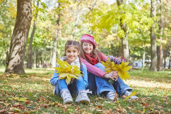 Chica con síndrome de Down y niña en el parque de otoño . — Foto de Stock