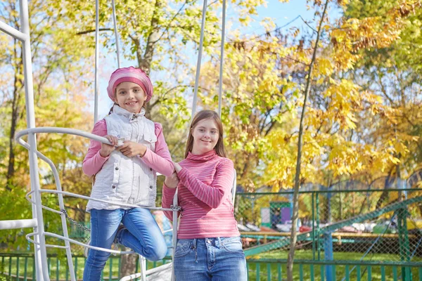 Dziewczyna z zespołem Downa i mała dziewczynka w jesiennym parku. — Zdjęcie stockowe