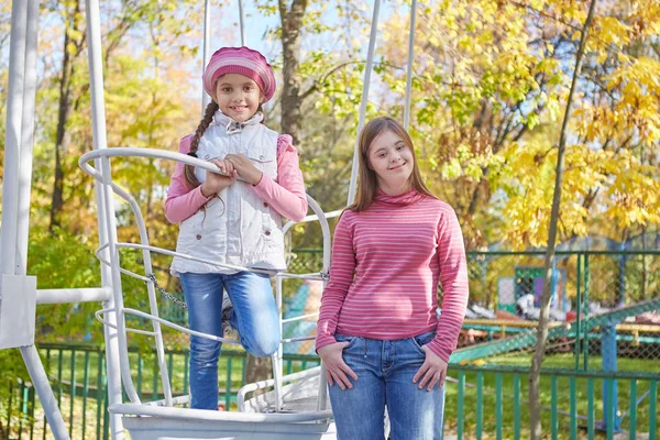 Girl with Down syndrome and little girl in autumn park. — Stock Photo, Image