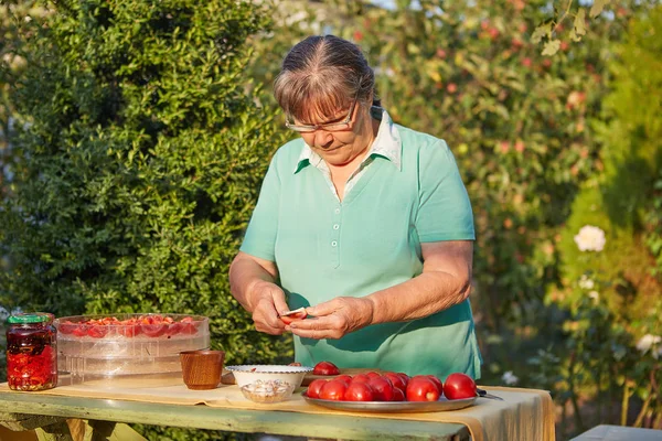 Woman in the garden cutting tomatoes — Stock Photo, Image