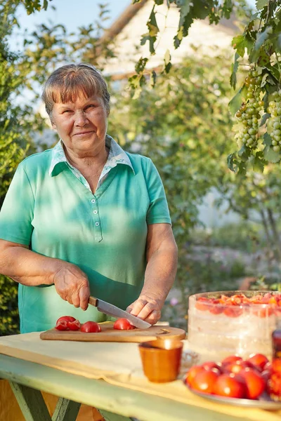 Woman in the garden cutting tomatoes — Stock Photo, Image