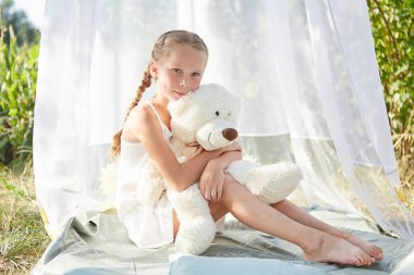 Oyuncak beyaz şifonlu çadırda küçük bir kız. Çocukluk, şefkat, güzellik.