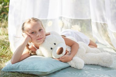 Oyuncak beyaz şifonlu çadırda küçük bir kız. Çocukluk, şefkat, güzellik.