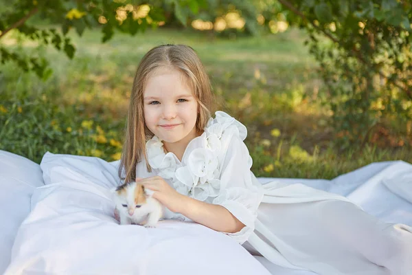 小さな女の子嘘でベッドで夏の庭で子猫 — ストック写真