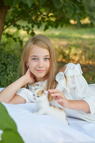 小さな女の子嘘でベッドで夏の庭で子猫 — ストック写真