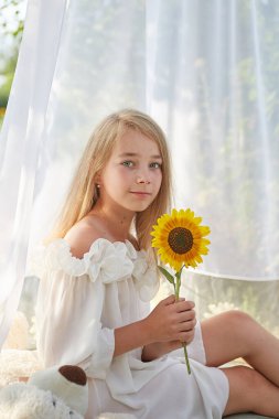 Ayçiçekli beyaz şifon çadırlı küçük kız. Çocukluk, şefkat, güzellik.