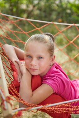 Küçük kız, güneşli bir yaz gününde hasır bir hamakta yatıyor..