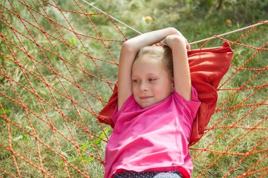 Küçük kız, güneşli bir yaz gününde hasır bir hamakta yatıyor..