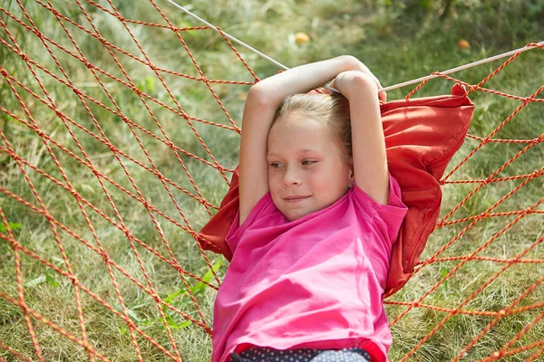Küçük kız, güneşli bir yaz gününde hasır bir hamakta yatıyor..