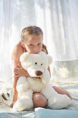 Oyuncak beyaz şifonlu çadırda küçük bir kız. Çocukluk, şefkat, güzellik.