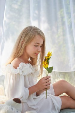 Ayçiçekli beyaz şifon çadırlı küçük kız. Çocukluk, şefkat, güzellik.