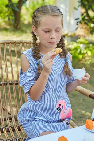 小さな女の子は夏の庭でお茶を飲みながらアームチェアに座っています お茶を飲む 楽しい — ストック写真