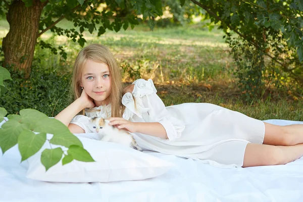 小さな女の子嘘でベッドで夏の庭で子猫 — ストック写真