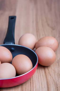 Tavada yumurta ve kahverengi ahşap arka plan