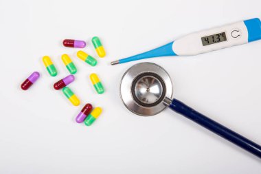 Stetoskop ve beyaz sırt üzerinde kapsül ile dijital termometre