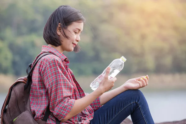 Woman tourist with backpack drinking water in nature
