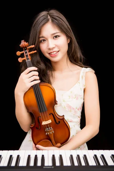 Asian woman and violin isolated over black background