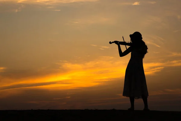 Силуэт азиатской женщины играет на скрипке на закате — стоковое фото