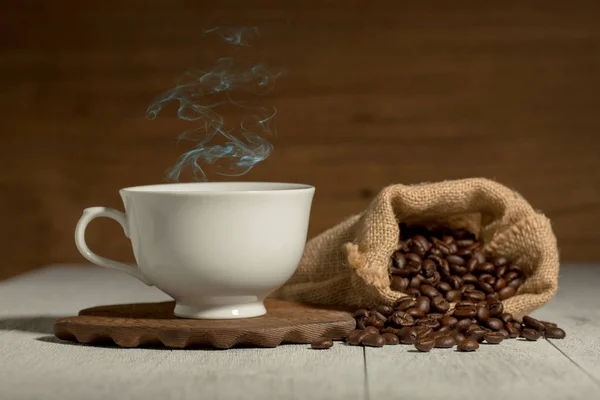 Xícara de café e grãos de café no fundo de madeira — Fotografia de Stock