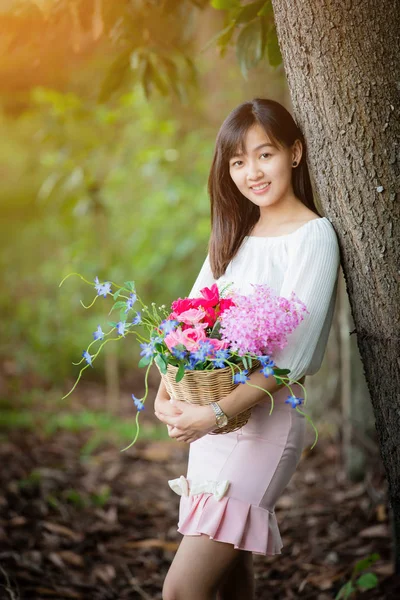Азиатская девушка с цветочком в саду с солнечным светом — стоковое фото