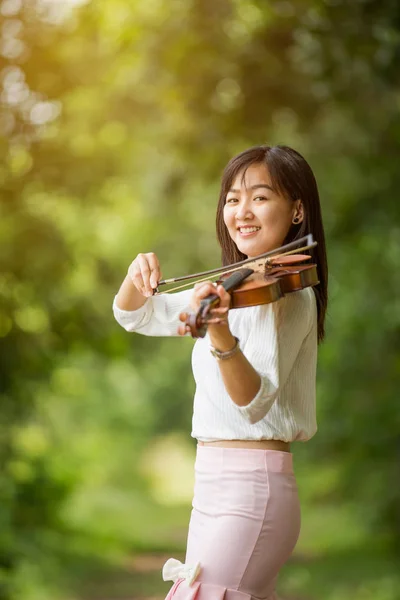 太陽の光を浴びて庭でバイオリンを弾くアジアの女性 — ストック写真