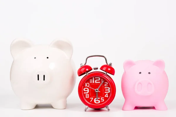 piggy bank and red alarm clock on white background
